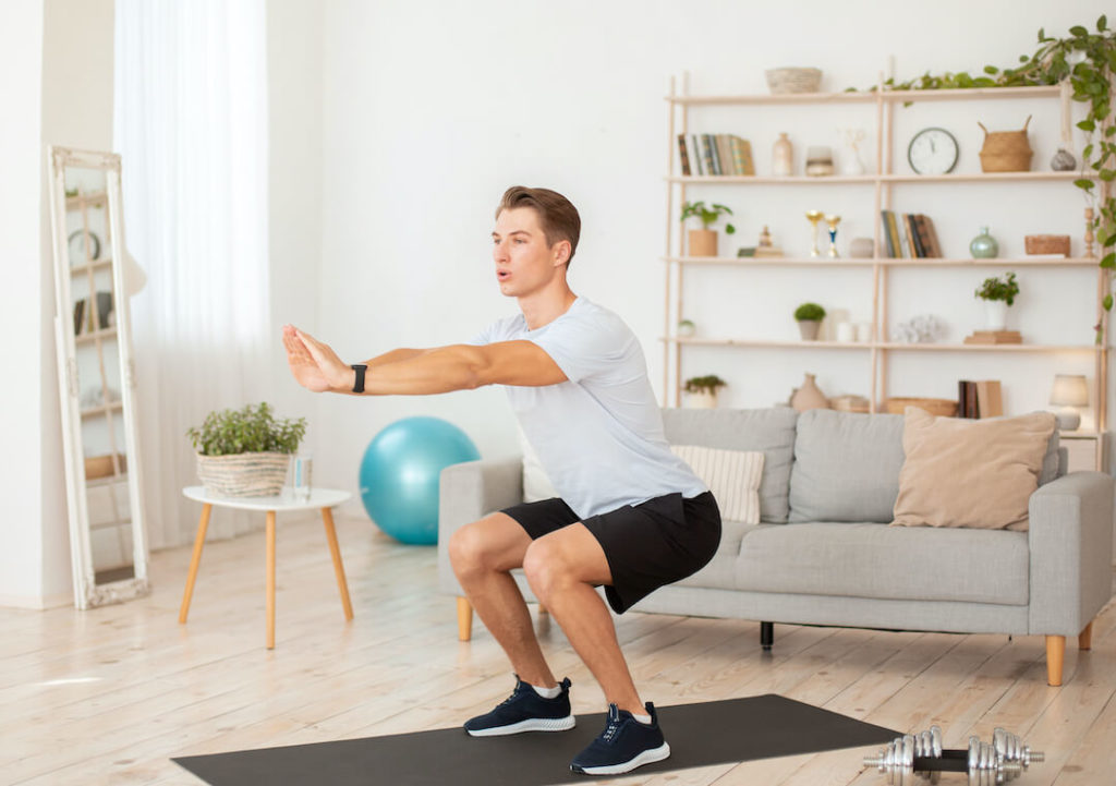Man Performing Squats Leg Workout Routine At Home