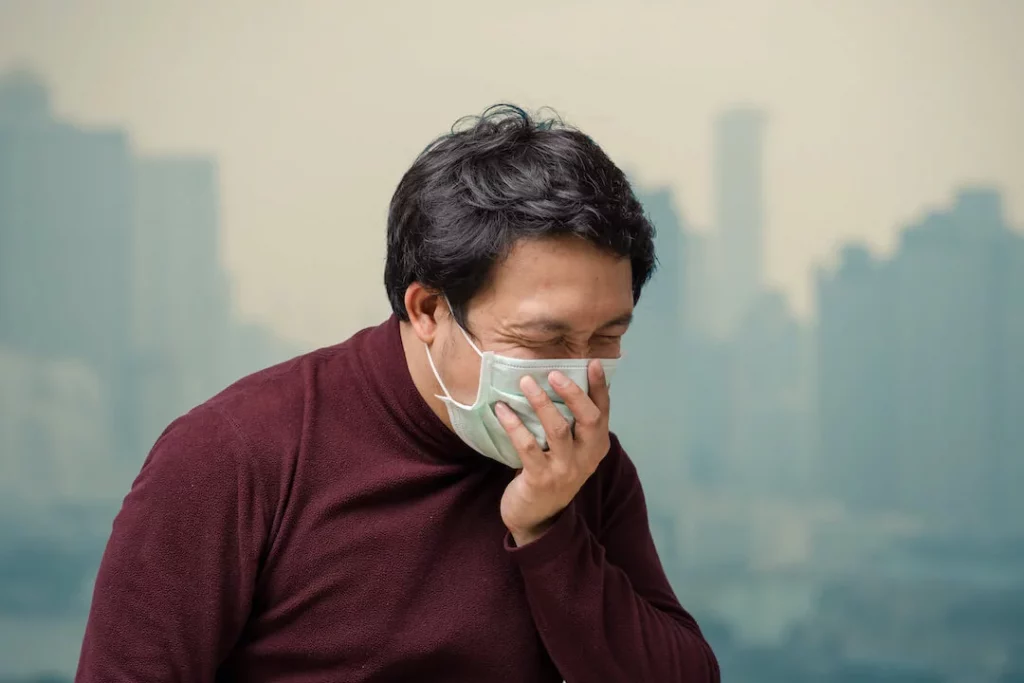 Sinus Causes - Man is coughing because of sinus caused by weather pollution